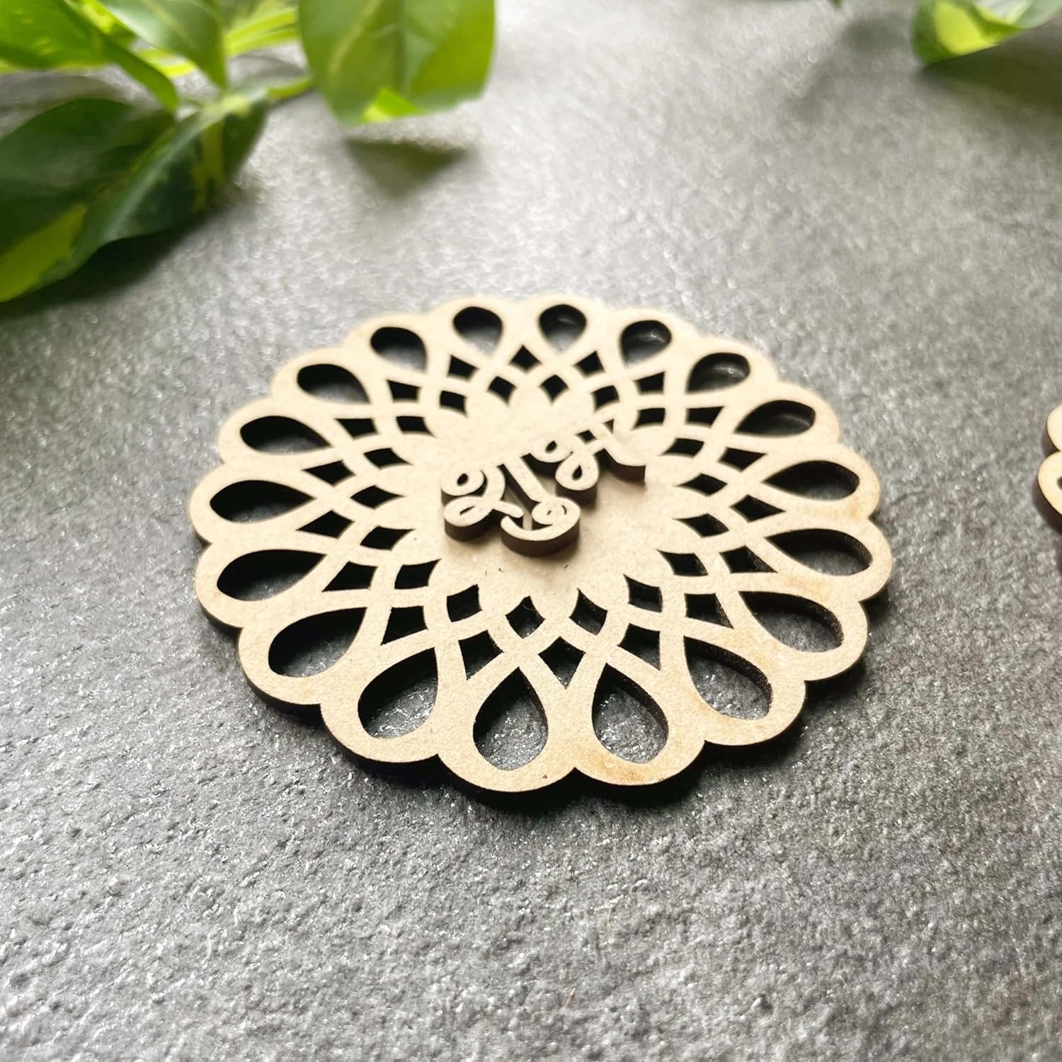 Decorative wooden coaster with intricate cut-out design on a gray surface.