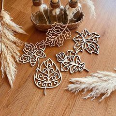 Decorative leaf-shaped objects on a wooden surface with pampas grass.