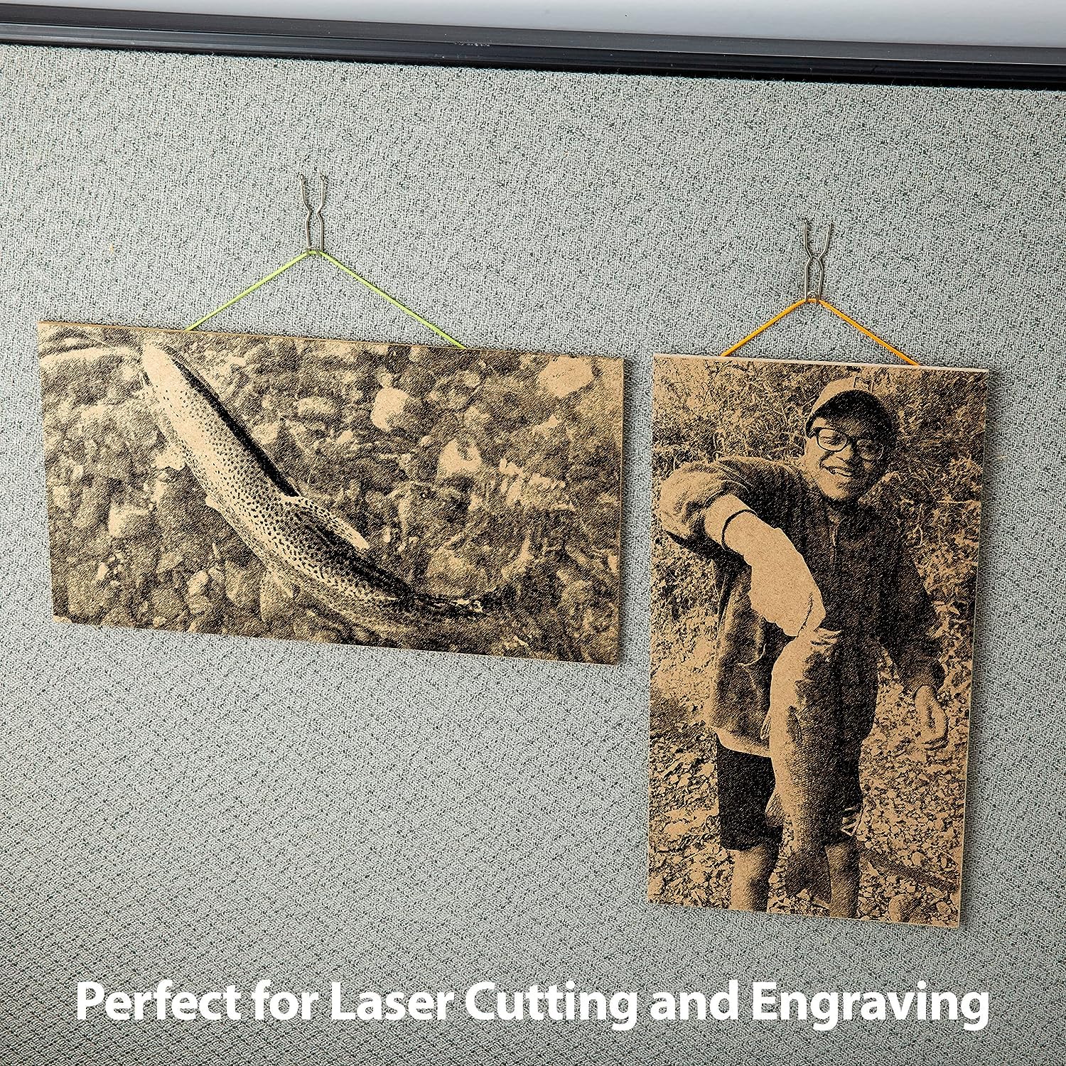 Two wooden plaques with laser-cut images of a fish and a person holding a fish, hanging on a textured wall.