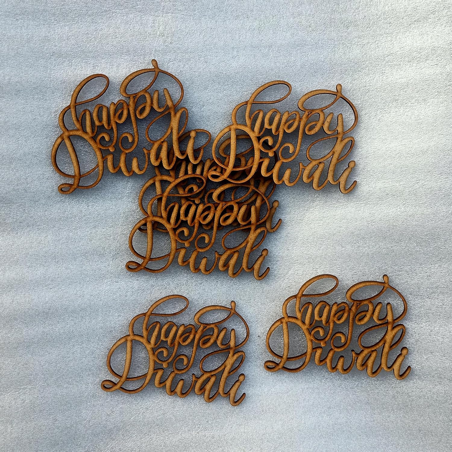Wooden 'Happy Diwali' decorations on a textured gray background