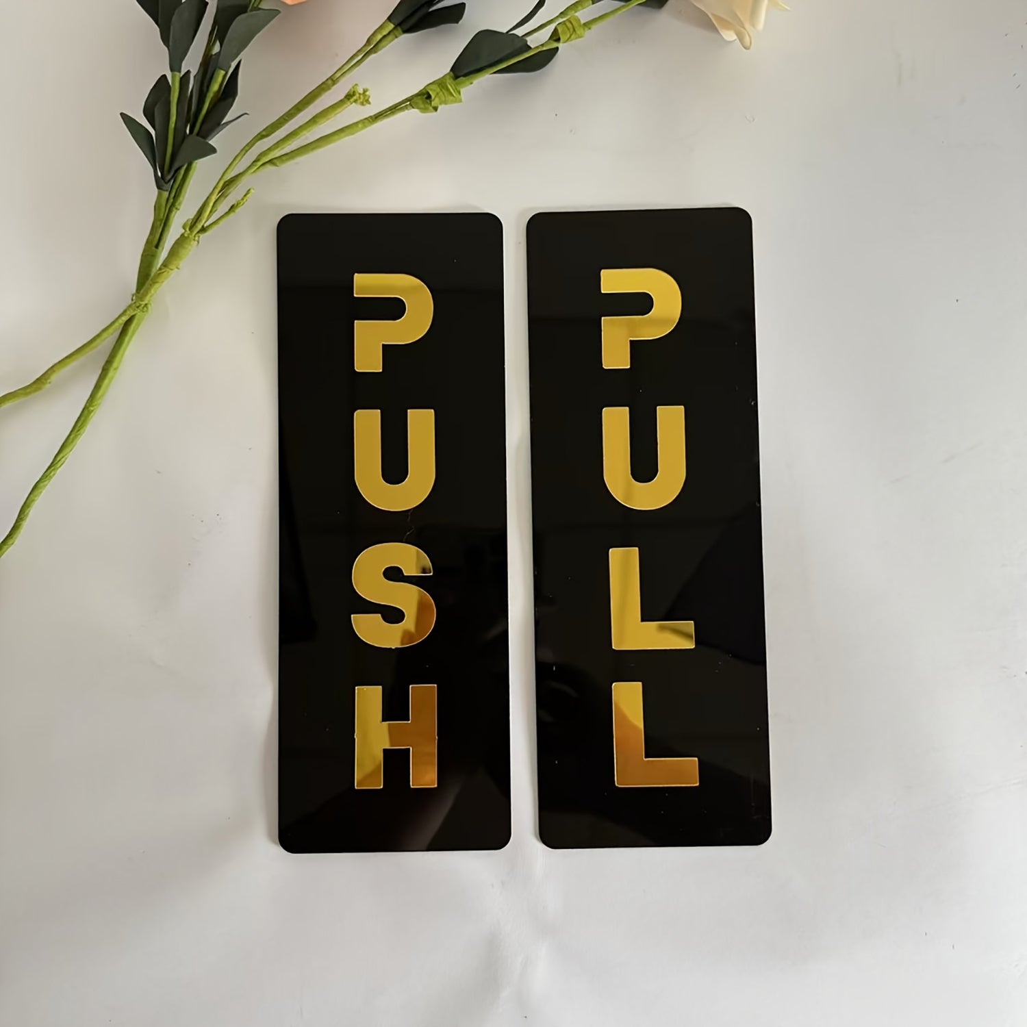 Two black rectangular signs with gold text 'PUSH' and 'PULL' on a white background.