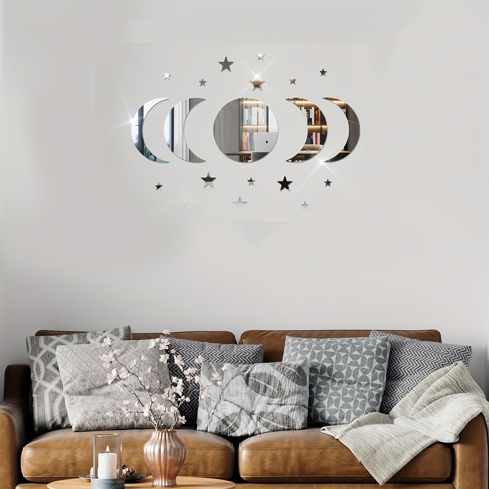 Decorative wall stickers with moon and star designs on a gray wall above a brown sofa with patterned cushions.