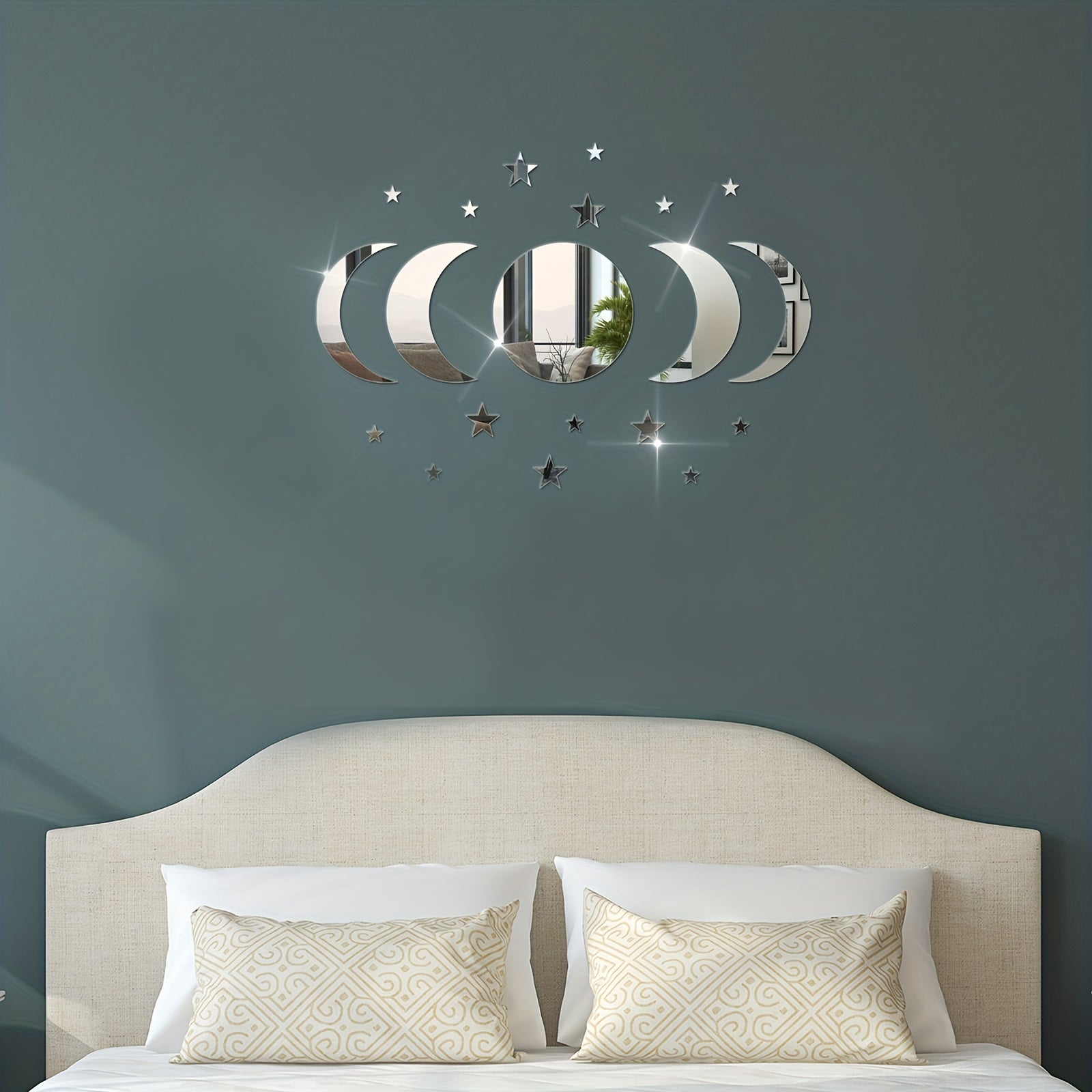 Decorative wall mirror with moon and star design above a bed with pillows.