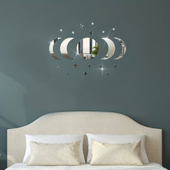 Decorative wall mirror with moon and star design above a bed with pillows.