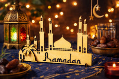Decorative Ramadan lantern with a mosque design on a table with dates and candles.