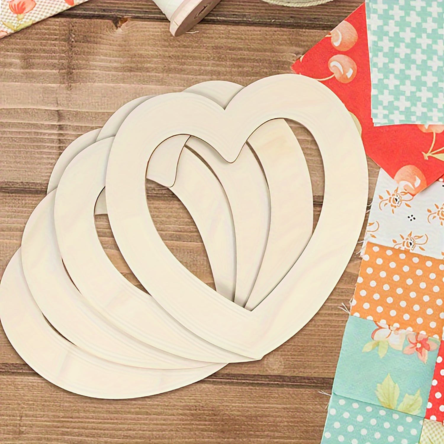 Wooden heart shapes on a wooden surface with colorful fabric swatches.
