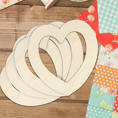 Wooden heart shapes on a wooden surface with colorful fabric swatches.