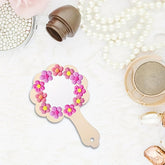 Handheld mirror with floral design on a white surface