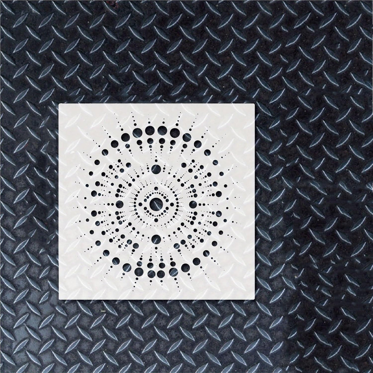 White square with black circular pattern on a textured black background