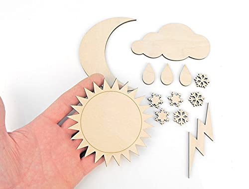Hand holding wooden sun and moon cutouts with additional weather-themed pieces on a white background