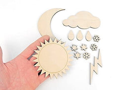 Hand holding wooden sun and moon cutouts with additional weather-themed pieces on a white background