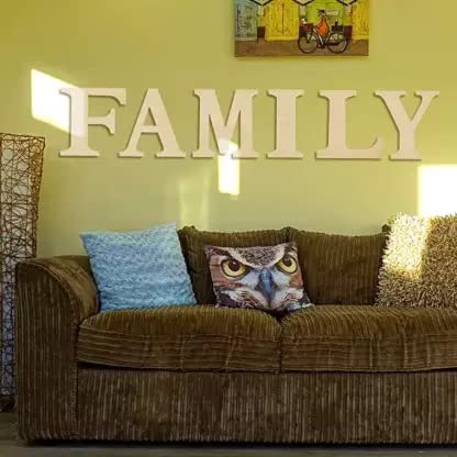 Brown sofa with decorative pillows against a light green wall with 'FAMILY' letters.