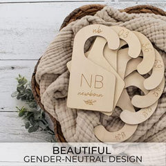 Wooden baby gender indicators with 'NB' and 'newborn' text on a textured fabric background.