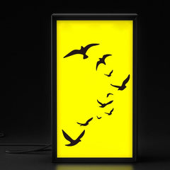 Framed artwork with black bird silhouettes on a yellow background
