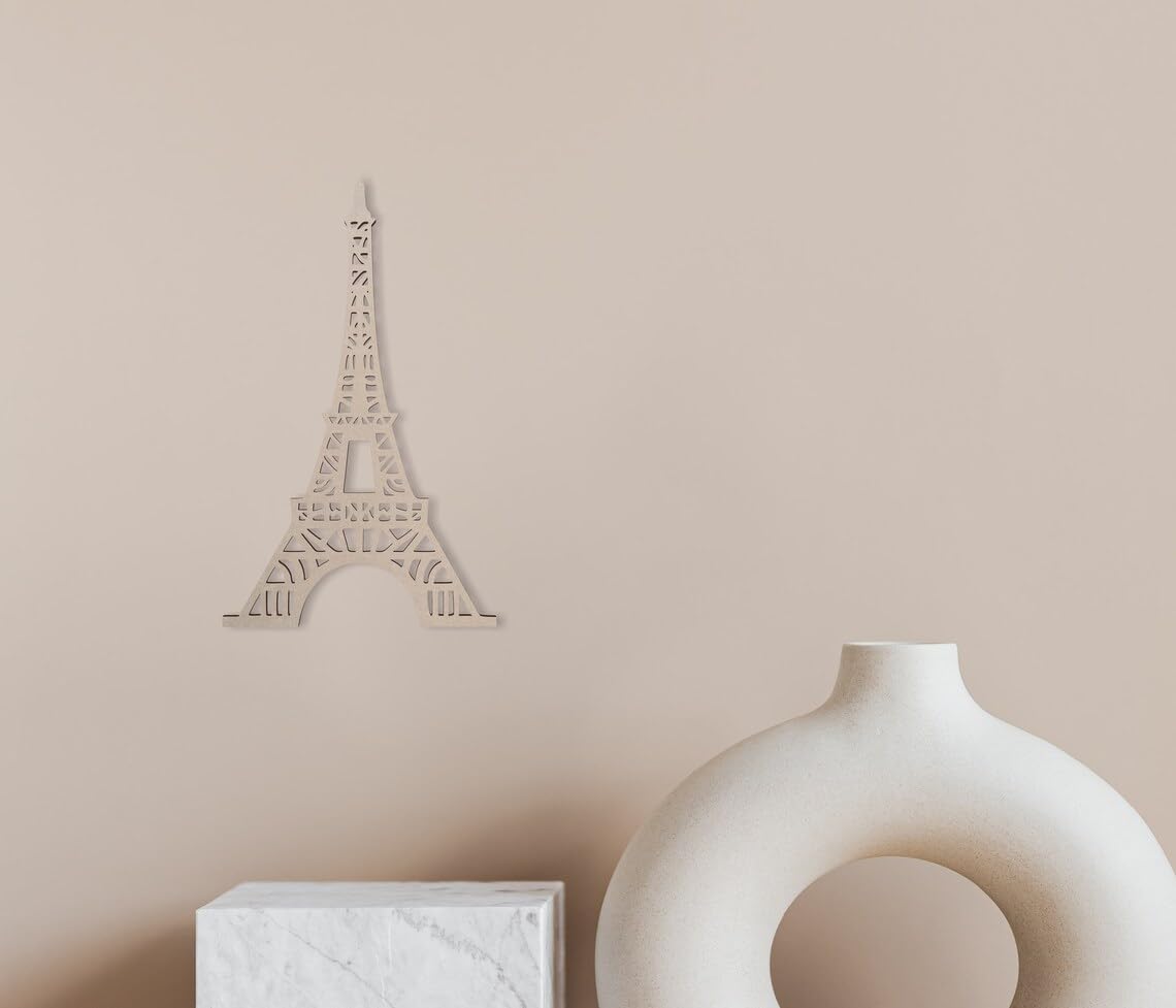 Decorative Eiffel Tower wall art on a beige wall with a white vase and box below.