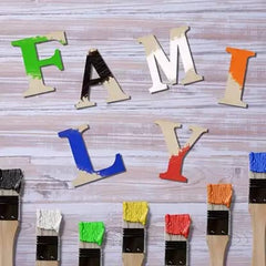 Colorful wooden letters spelling 'FAMILY' on a wooden background with paintbrushes.