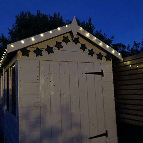 Wooden shed with decorative star patterns and string lights against a dark sky.