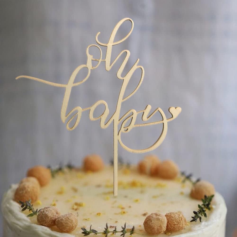 Gold 'oh my baby' cake topper on a decorated cake with a blurred background