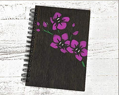 Black notebook with purple floral design on a white wooden surface