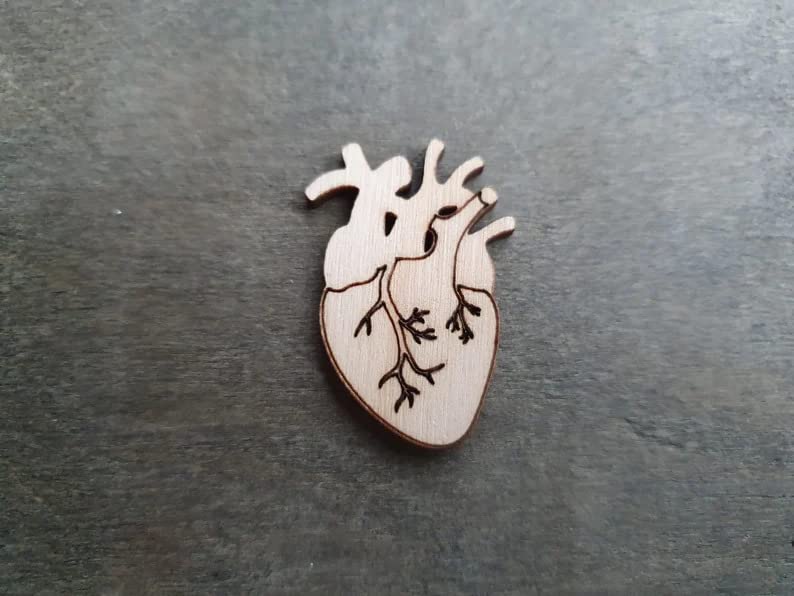 Wooden anatomical heart pin on a dark surface