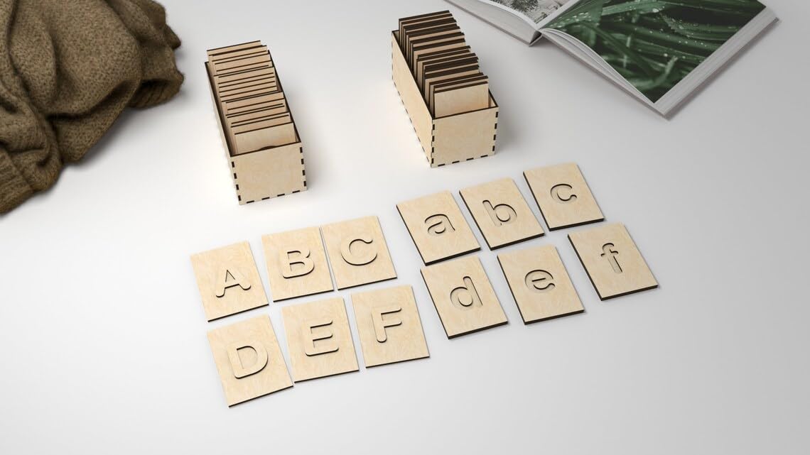 Wooden letter tiles on a white surface with cardboard boxes and a magazine in the background.