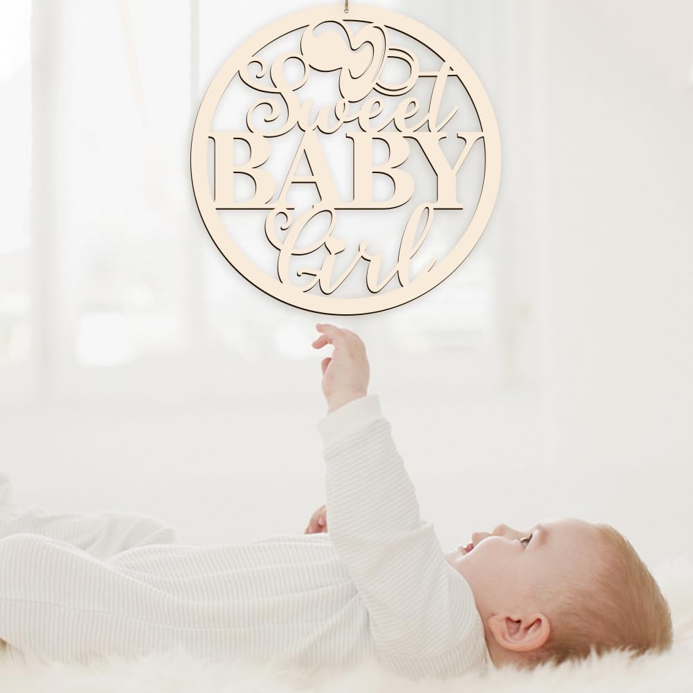 Baby reaching towards a 'Sweet Baby Girl' wooden sign on a white background