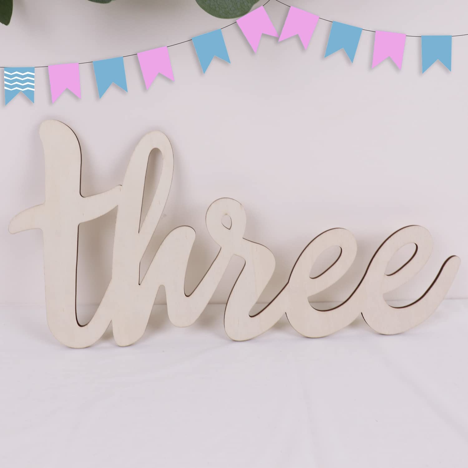 Wooden number 'three' with a colorful banner in the background