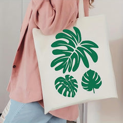 Person holding a tote bag with green leaf patterns
