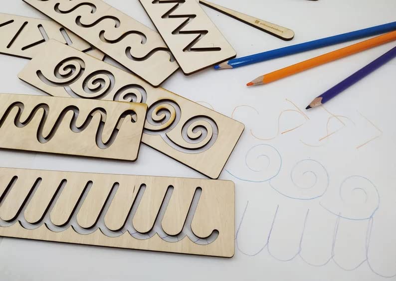 Wooden templates with cut-out patterns and colored pencils on a white surface