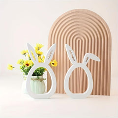 Decorative bunny-shaped vases with plants against a beige arch-shaped wall.