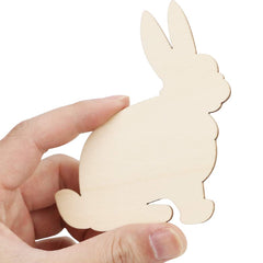 Hand holding a wooden rabbit cutout against a white background