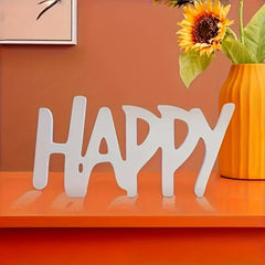 Decorative word 'HAPPY' on an orange surface with a sunflower in the background.