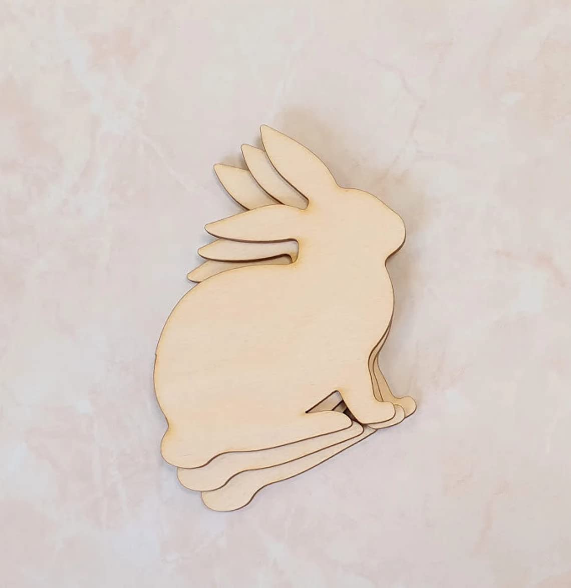 Wooden rabbit cutout on a light pink background