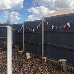 Fence with colorful triangular flags against a blue sky with clouds