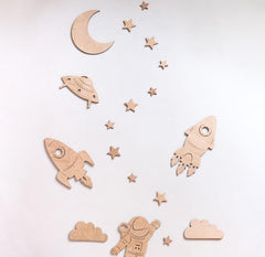 Wooden space-themed decorations including rockets, a moon, stars, and an astronaut on a light background.