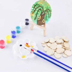 Art supplies including a small easel with a painted tree, paint jars, brushes, and gold coins on a white background.