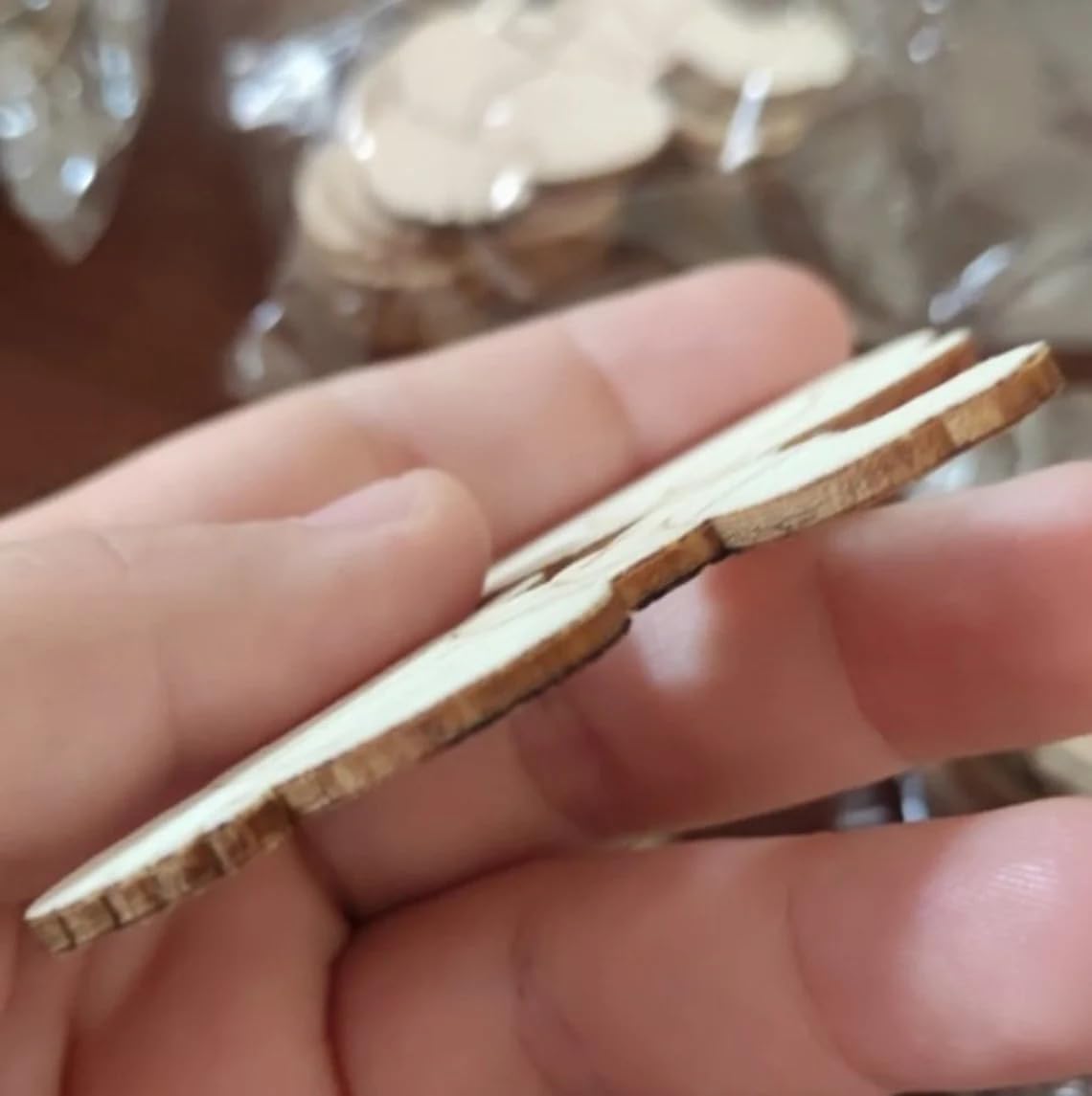 Close-up of a hand holding a thin slice of wood with a blurred background