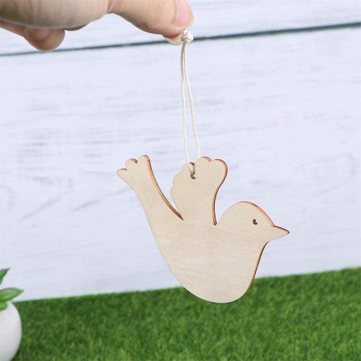 Wooden bird ornament hanging from a string with a blurred background