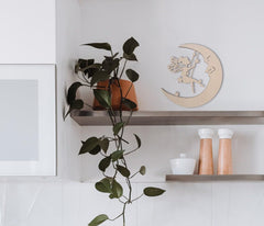 Shelving unit with decorative items including a plant, moon-shaped wall art, and cylindrical objects.