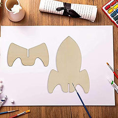 Wooden rocket shape on a white sheet of paper with art supplies around