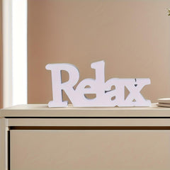 White 'Relax' sign on a beige surface with a neutral background