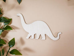 White dinosaur toy on a beige background with green leaves