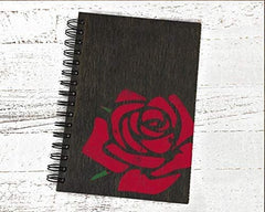 Notebook with a red rose design on a white wooden surface