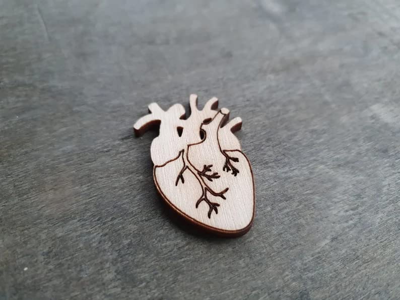 Wooden heart-shaped object with cut-out design on a gray surface