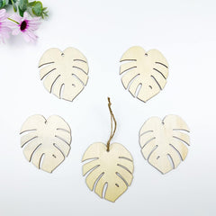 Set of wooden monstera leaf decorations on a white background