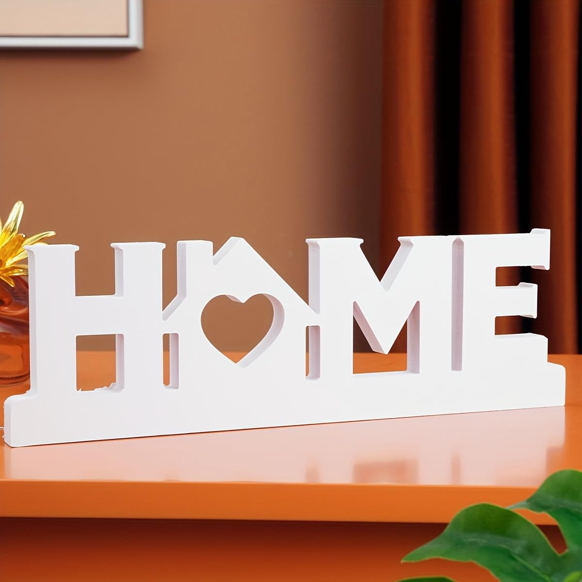 Decorative sign with 'HOME' and heart design on a wooden surface.