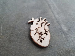 Wooden heart-shaped pin with intricate design on a gray surface