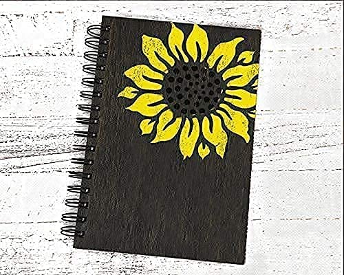 Black notebook with a yellow sunflower design on a white wooden surface