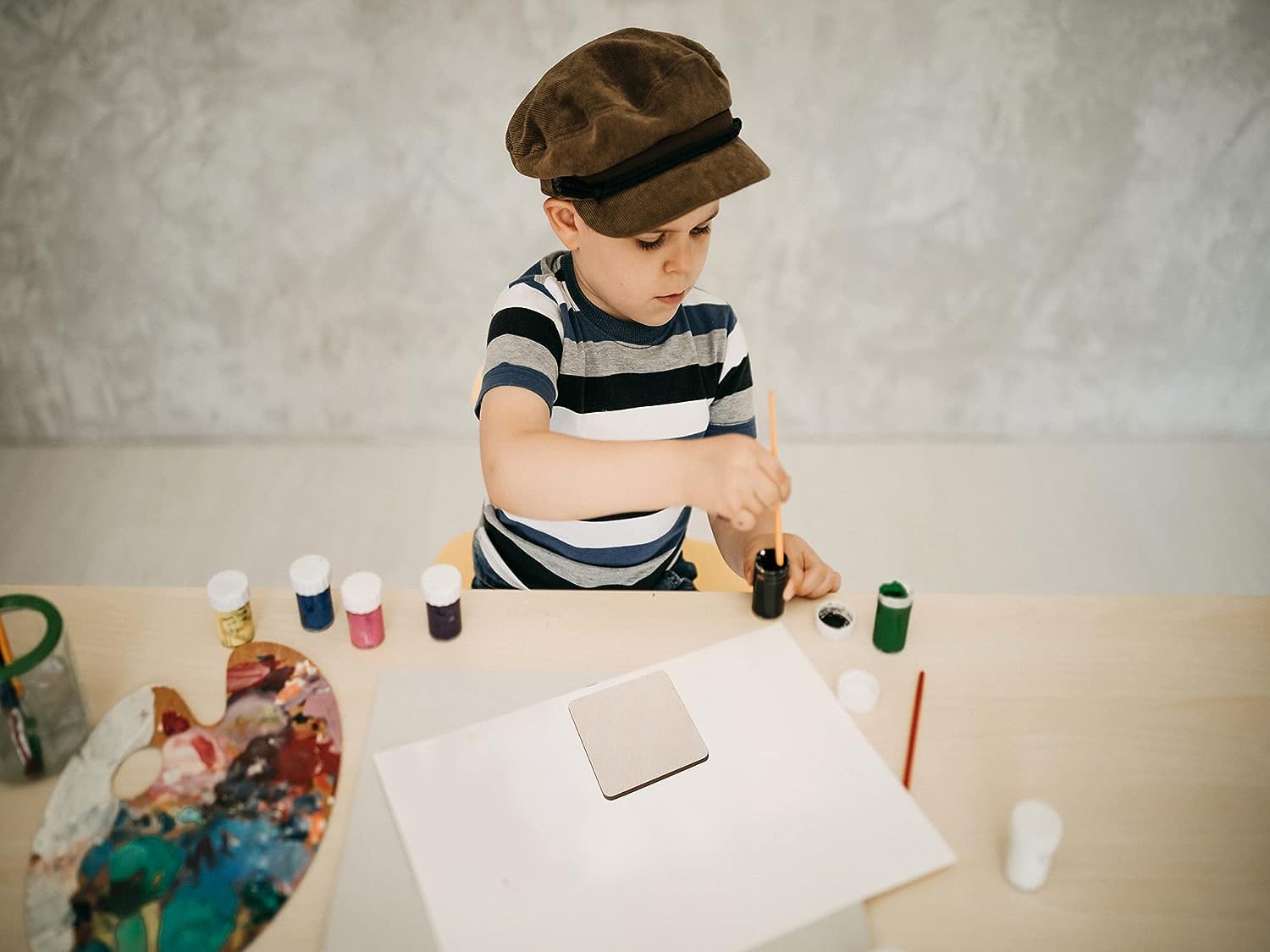 Child painting at a table with art supplies