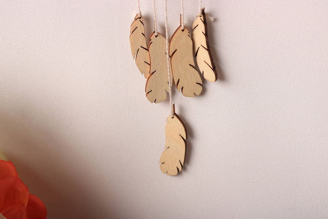 Wooden feather decorations hanging against a plain background